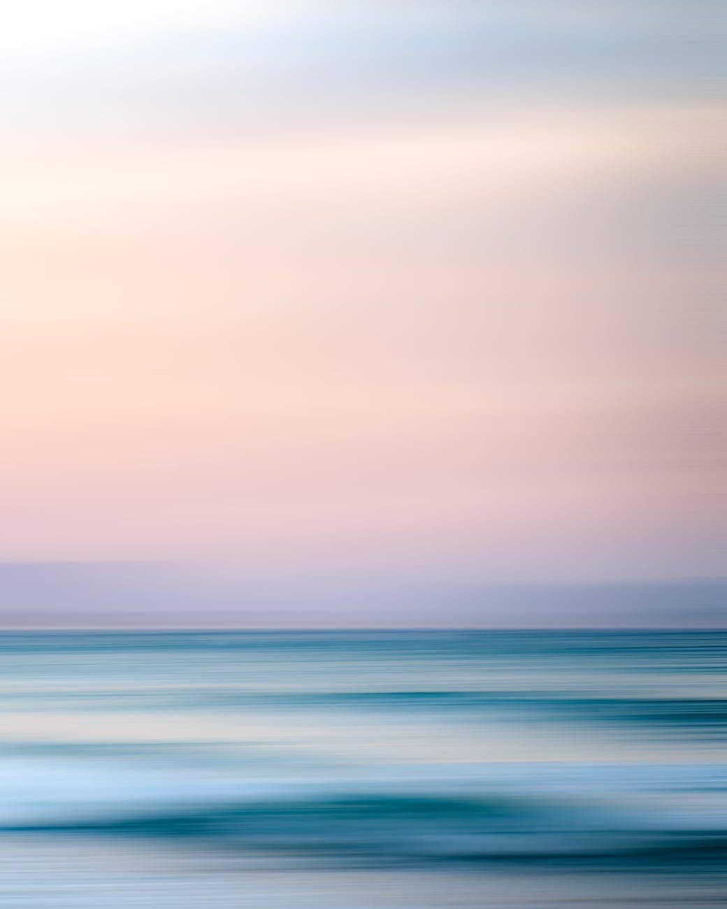 magnificent view of ocean beneath light pink sky