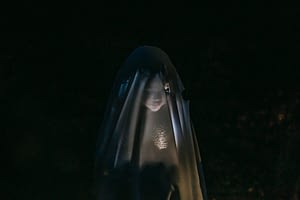 mysterious child shining flashlight on face covered with blanket